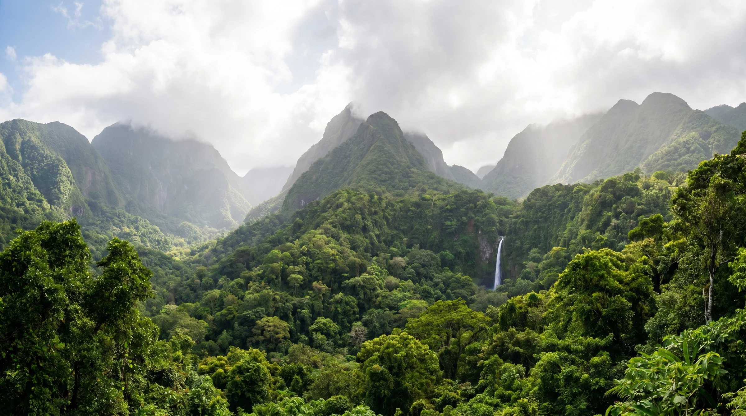 A Dominica rainforest panorama with the Morne Trois Pitons mountains and a distant waterfall — the natural landscape that defines the Nature Isle.