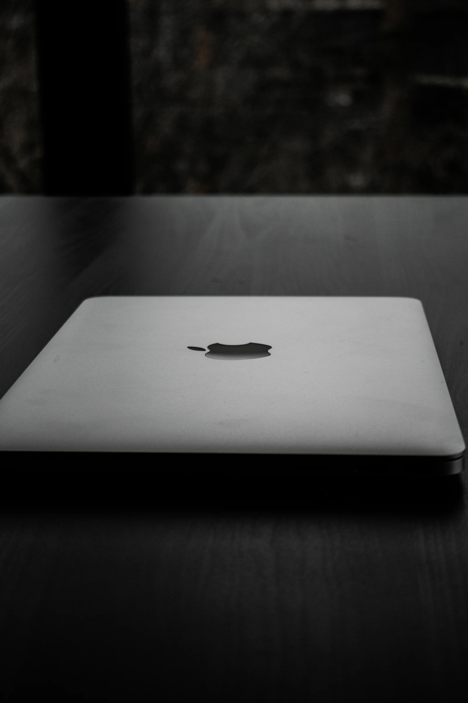 A minimalist laptop on a wood desk displaying an abstract interface — the visual register of the St Kitts and Nevis CIU's new digital platform.